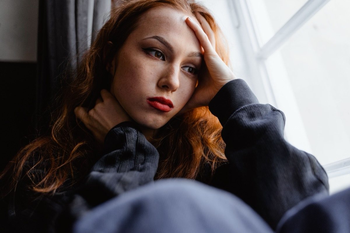 A teen resting her head on her hand, looking out a window